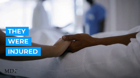 Two people holding hands in a hospital bed.