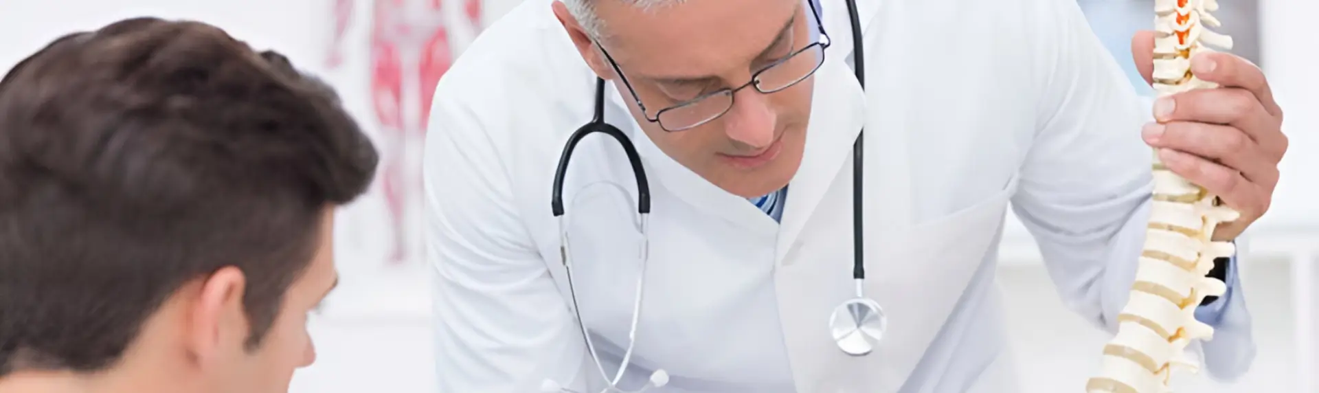 A doctor is looking down at his stethoscope.