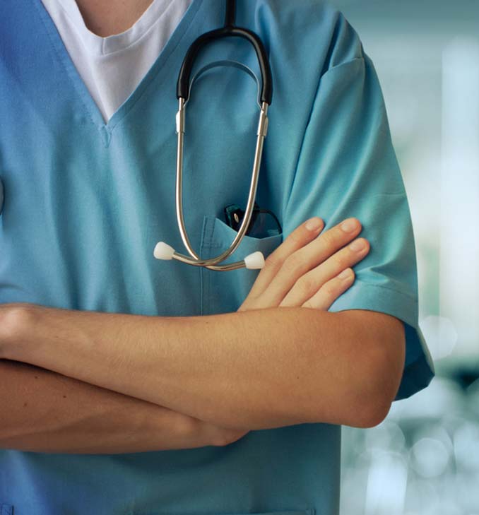 A doctor with his arms crossed wearing blue scrubs.